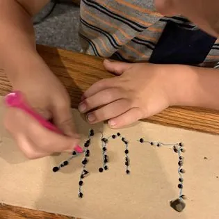 Close-up of a child's hands practising pencil control and letter formation during occupational therapy
